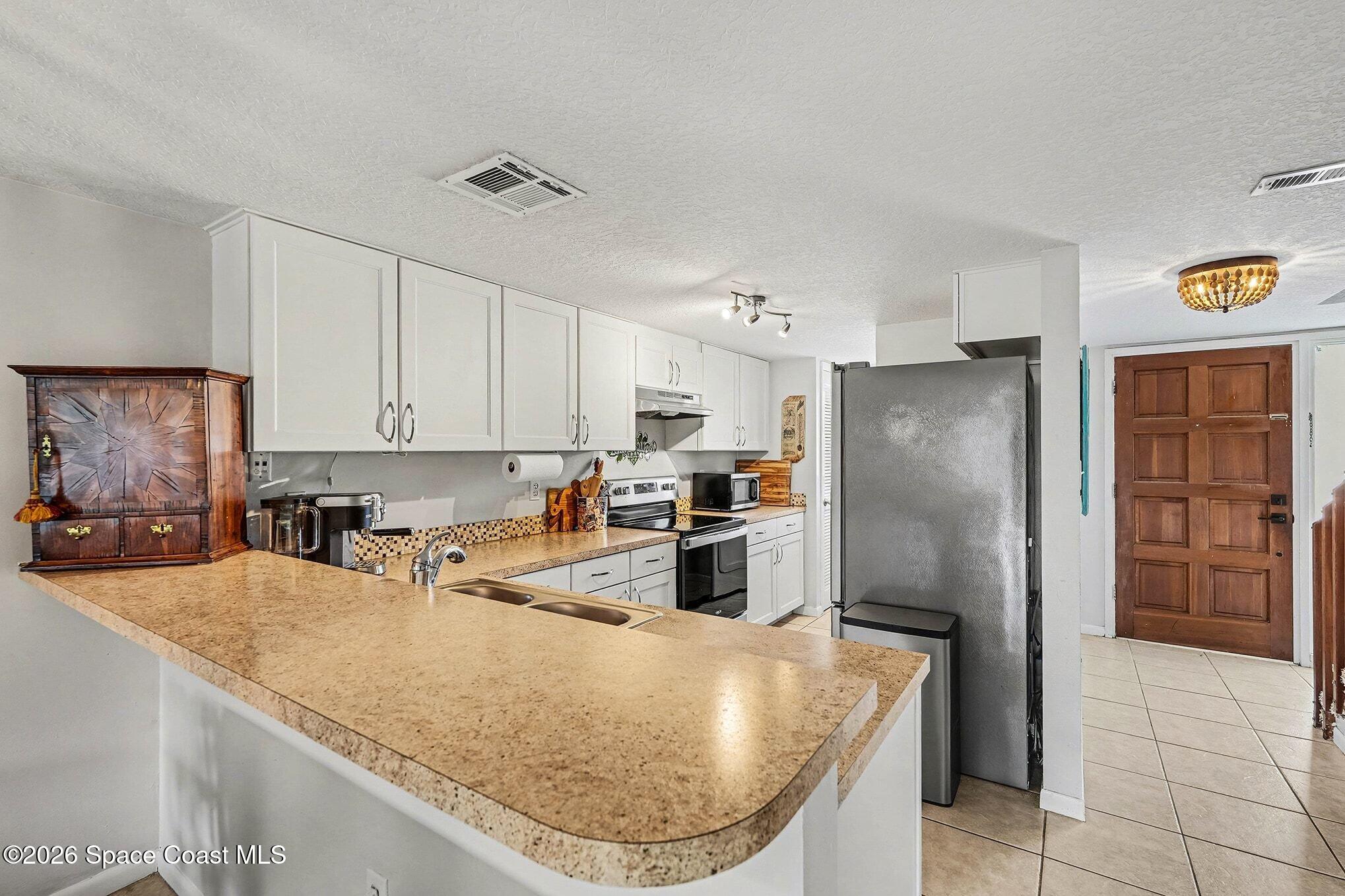 290 North 2nd Street, Unit 3 Cocoa Beach, FL 32931 - Photo 12 of 31 a kitchen with stainless steel appliances granite countertop a sink a refrigerator and a stove