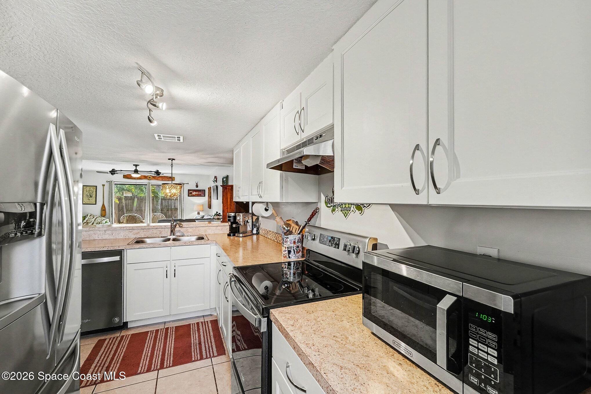 290 North 2nd Street, Unit 3 Cocoa Beach, FL 32931 - Photo 13 of 31 a kitchen that has a lot of white cabinets and stainless steel appliances