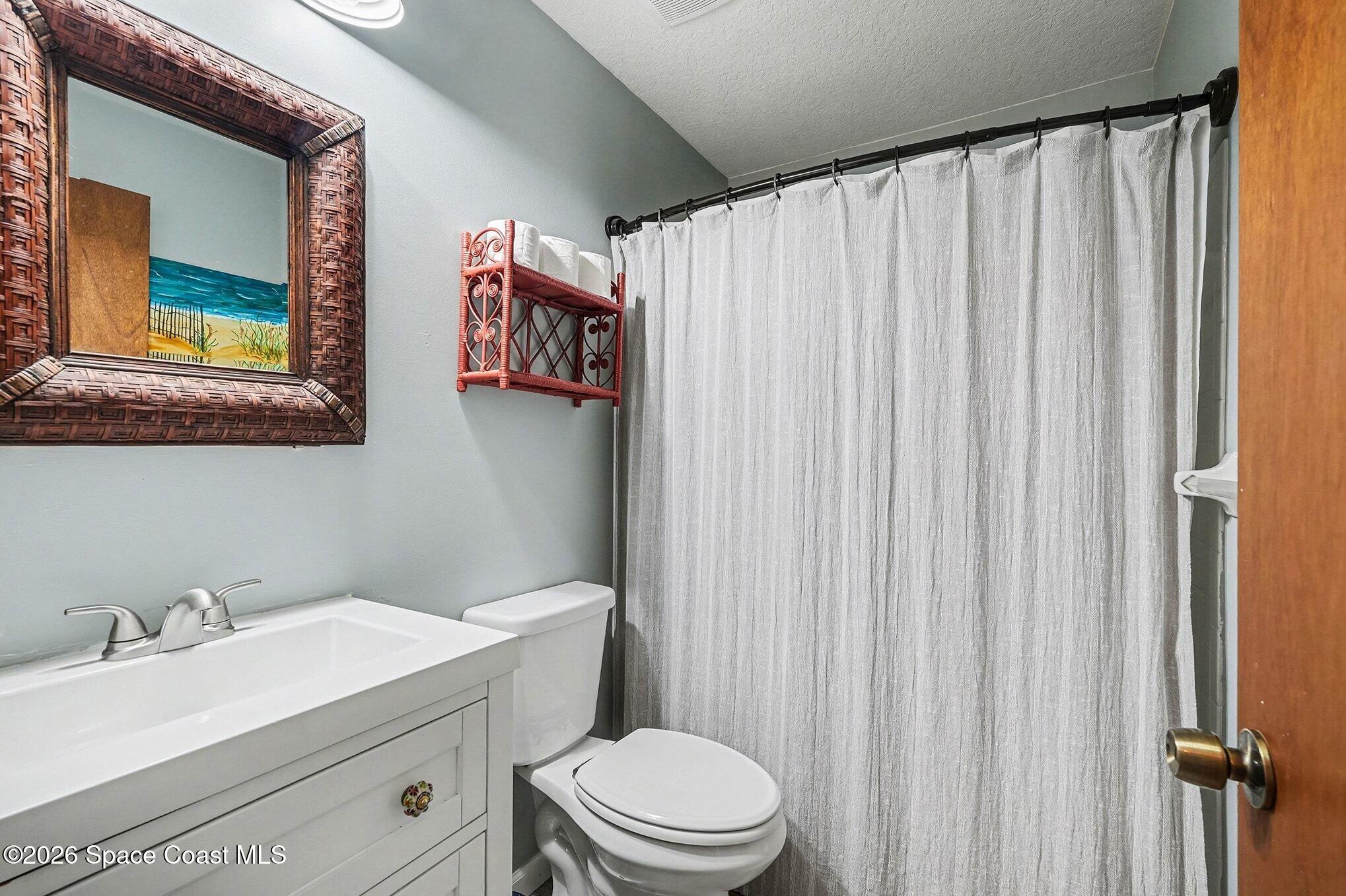 290 North 2nd Street, Unit 3 Cocoa Beach, FL 32931 - Photo 28 of 31 a bathroom with a sink a toilet and shower curtain