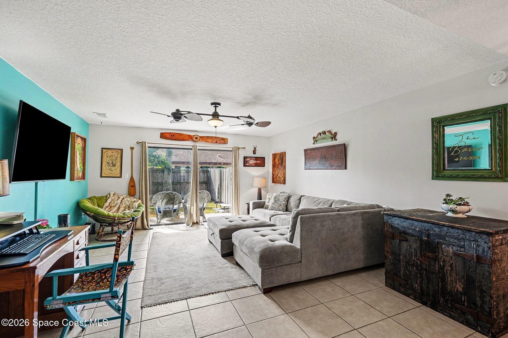 290 North 2nd Street, Unit 3 Cocoa Beach, FL 32931 - Photo 6 of 31 a living room with furniture a flat screen tv and floor to ceiling window
