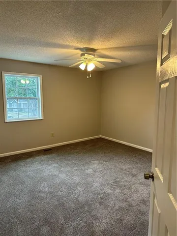 an empty room with a fan & a window