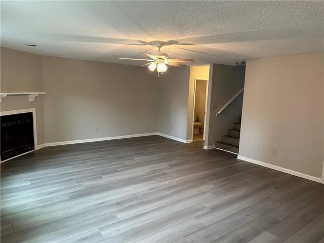 an empty room with wooden floor fireplace and windows