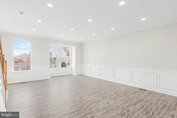 a view of an empty room with wooden floor and windows