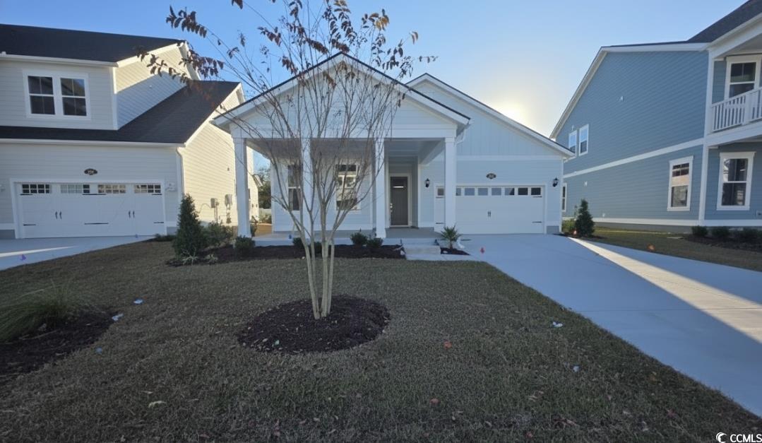 View of front of property with covered porch, concrete driveway, and a garage