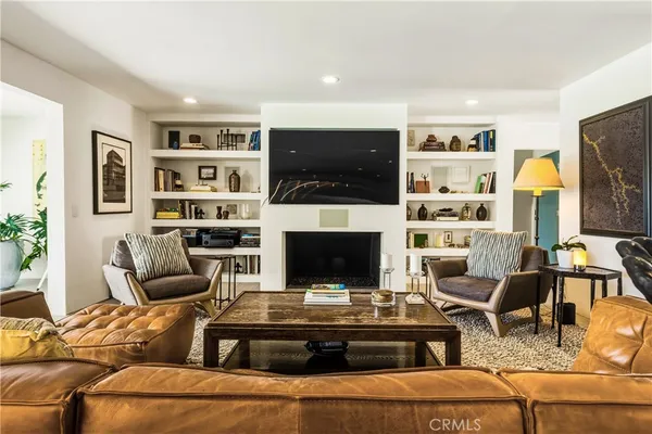 a living room with furniture a flat screen tv and kitchen view