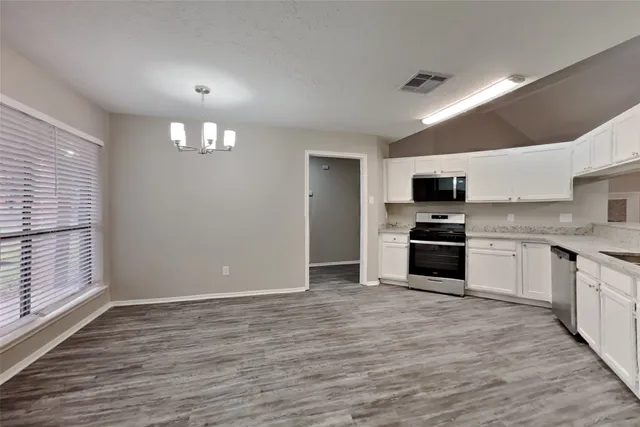 a kitchen with granite countertop a stove top oven and cabinets