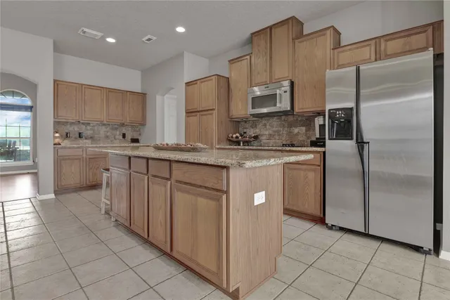 a kitchen with stainless steel appliances granite countertop a sink a stove and a refrigerator