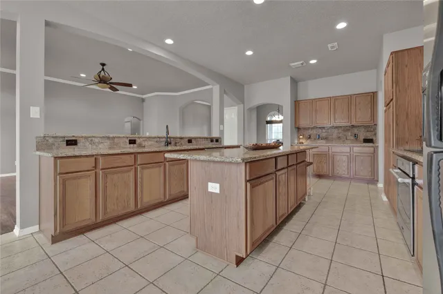 a kitchen with stainless steel appliances granite countertop a stove top oven island a refrigerator and cabinets