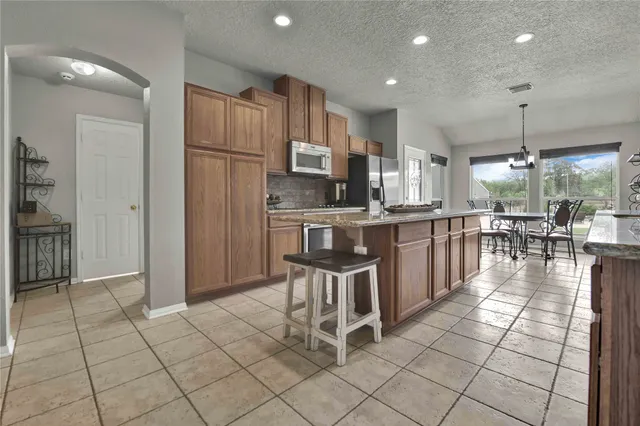 a kitchen with stainless steel appliances granite countertop a refrigerator and a stove top oven