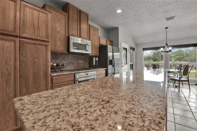 a large kitchen with a counter space a sink appliances and cabinets