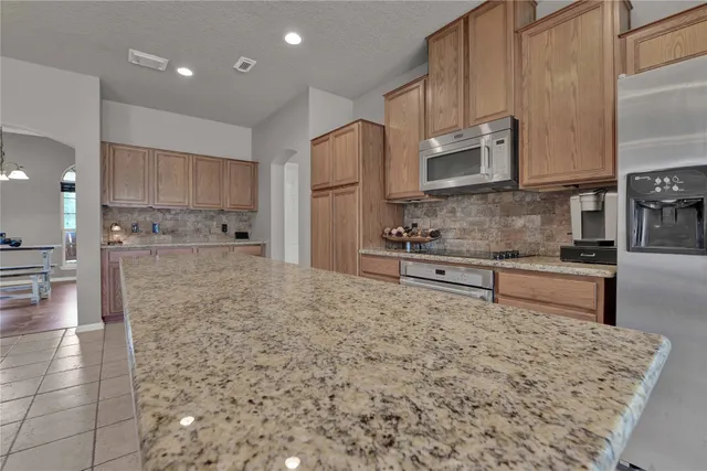 a large kitchen with kitchen island sink refrigerator and cabinets