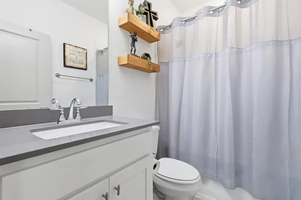 a bathroom with a sink a toilet and shower curtain