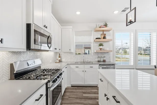 a kitchen with stainless steel appliances granite countertop a stove a sink and a microwave