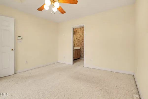 an empty room with a chandelier fan and windows