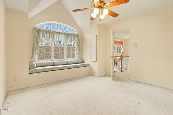 an empty room with windows and chandelier fan