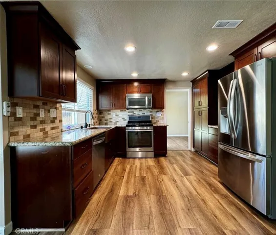 a large kitchen with stainless steel appliances granite countertop a stove refrigerator and microwave