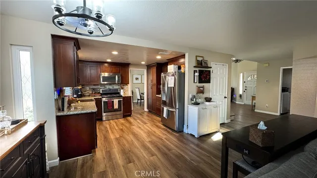 a kitchen with stainless steel appliances kitchen island granite countertop a refrigerator a stove top oven a sink and dishwasher