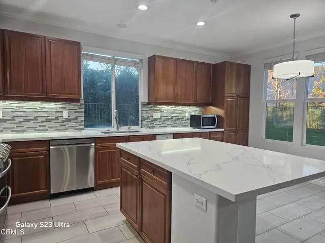 a kitchen with kitchen island granite countertop a sink a counter top space and cabinets