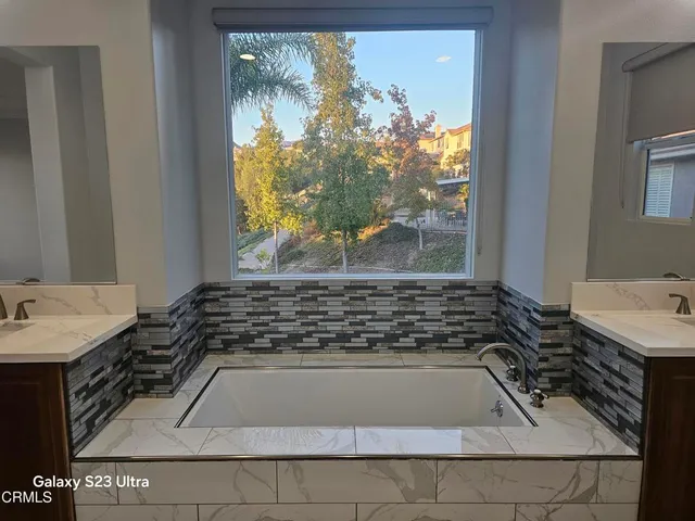 a bathroom with a granite countertop sink and a window