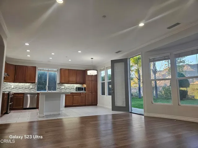 a view of kitchen with stainless steel appliances granite countertop a large counter top and a wooden floors