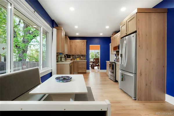 a kitchen with stainless steel appliances granite countertop a refrigerator a stove and a sink with wooden floor