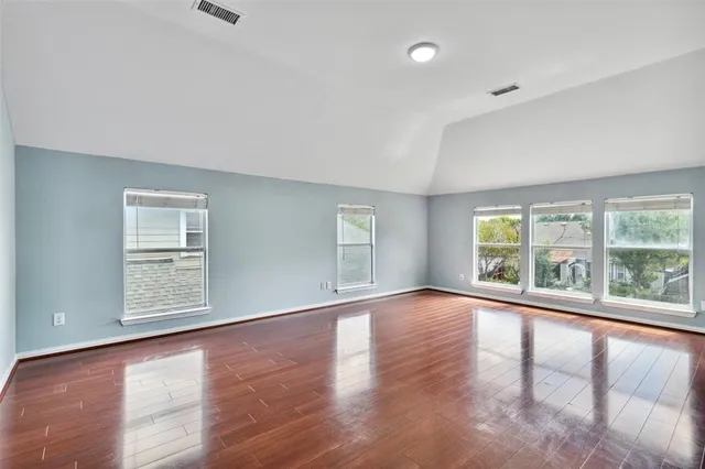 an empty room with wooden floor and natural light