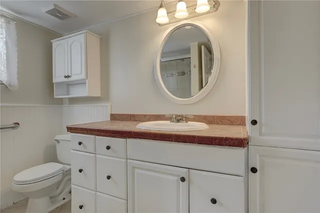 a bathroom with a granite countertop toilet sink and mirror