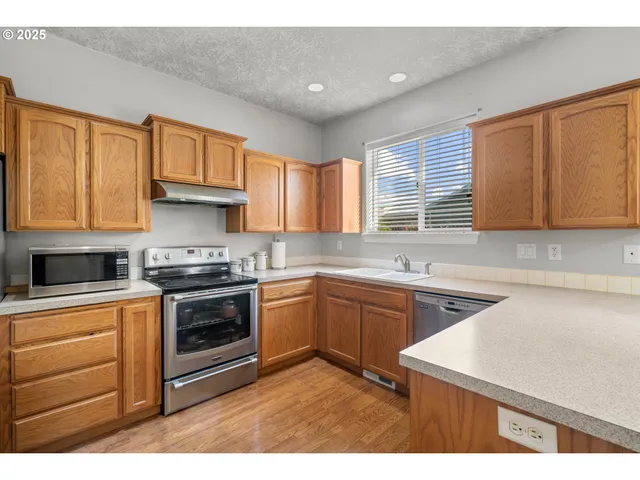 a kitchen with stainless steel appliances granite countertop a stove a sink and a microwave