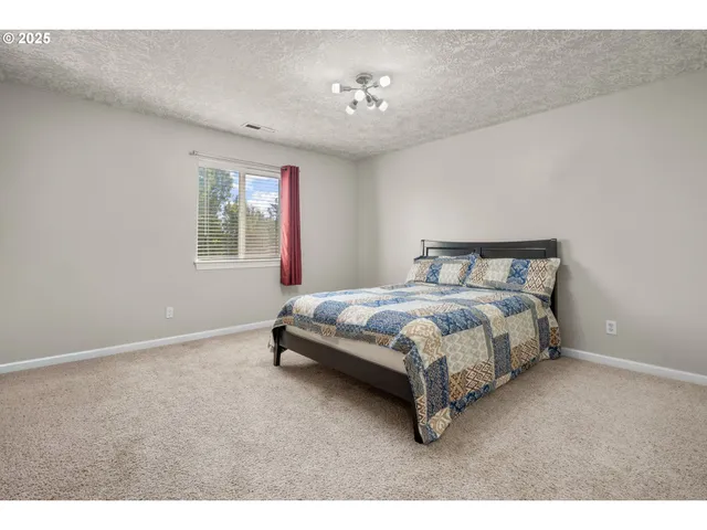 a spacious bedroom with a bed and lamp