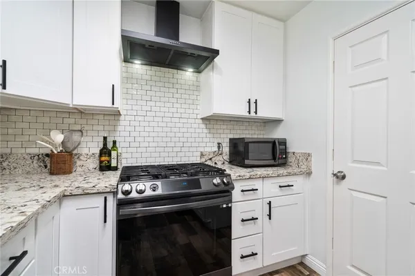 a kitchen with granite countertop a stove sink and cabinets