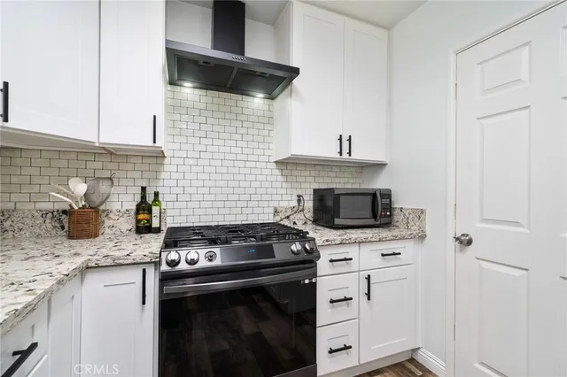 a kitchen with granite countertop a stove sink and cabinets