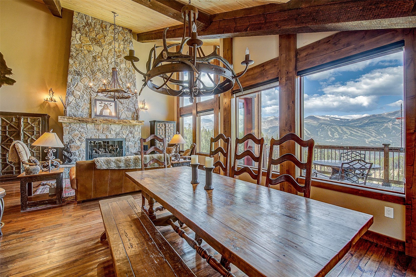 59 Club House Road, Unit C Breckenridge, CO 80424 - Photo 31 of 50 Dining space featuring a stone fireplace, dark wood-style flooring, a towering ceiling, a chandelier, and a wooden ceiling with exposed beams