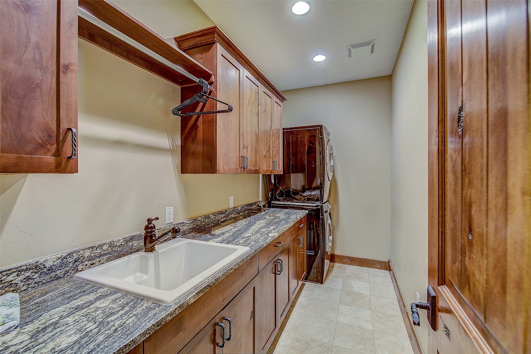 59 Club House Road, Unit C Breckenridge, CO 80424 - Photo 34 of 50 with dark stone counters, brown cabinetry, recessed lighting, washer / dryer, and light tile patterned floors