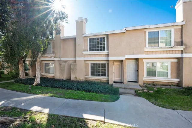 a view of a brick house next to a yard with potted plants