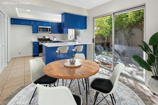 a open kitchen with stainless steel appliances granite countertop a stove a refrigerator a kitchen island a table and chairs in it