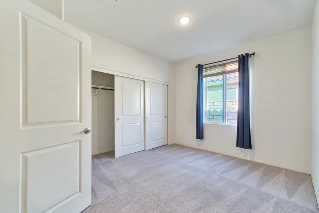 a view of an empty room with wooden floor and kitchen