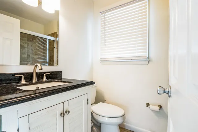 a bathroom with a granite countertop sink toilet and mirror
