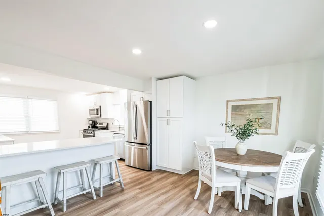 a kitchen with white cabinets and wooden floor