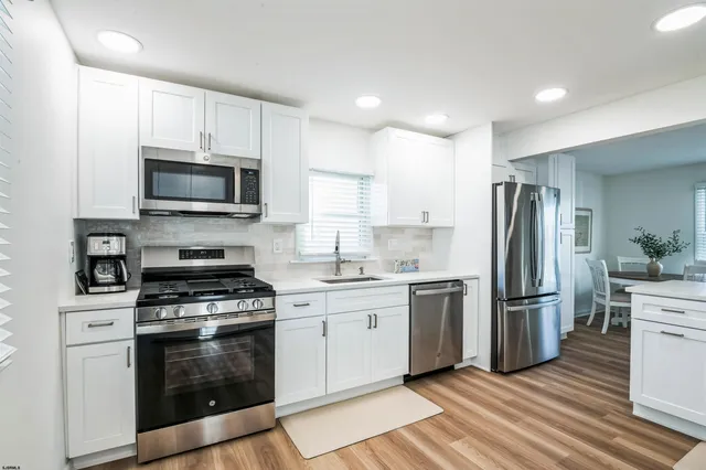 a kitchen with stainless steel appliances a refrigerator a stove top oven a sink and cabinets