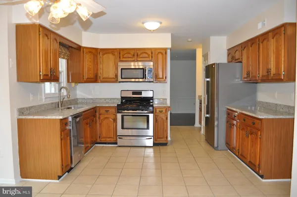 a kitchen with granite countertop cabinets stainless steel appliances a sink and a window