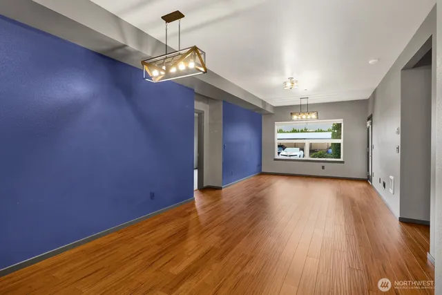 an empty room with wooden floor chandelier and windows