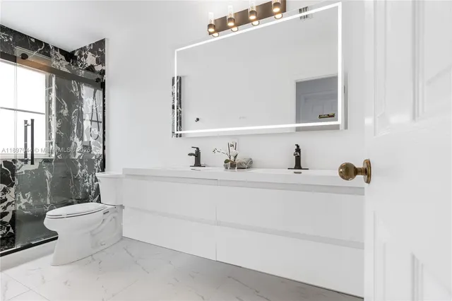 a bathroom with a sink mirror toilet and next to a window