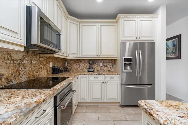 a kitchen with granite countertop a refrigerator stove and microwave