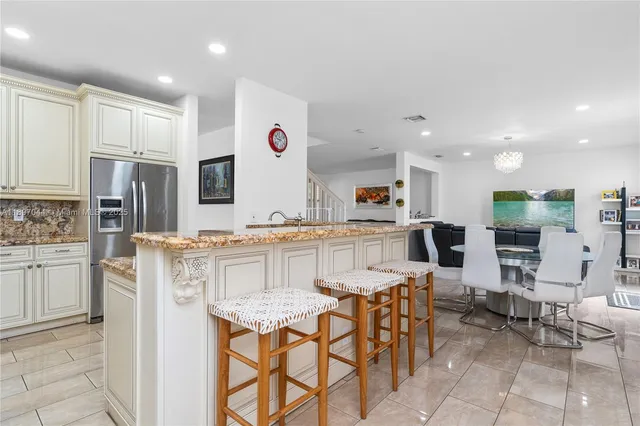 a kitchen with stainless steel appliances kitchen island granite countertop a kitchen island and chairs in it