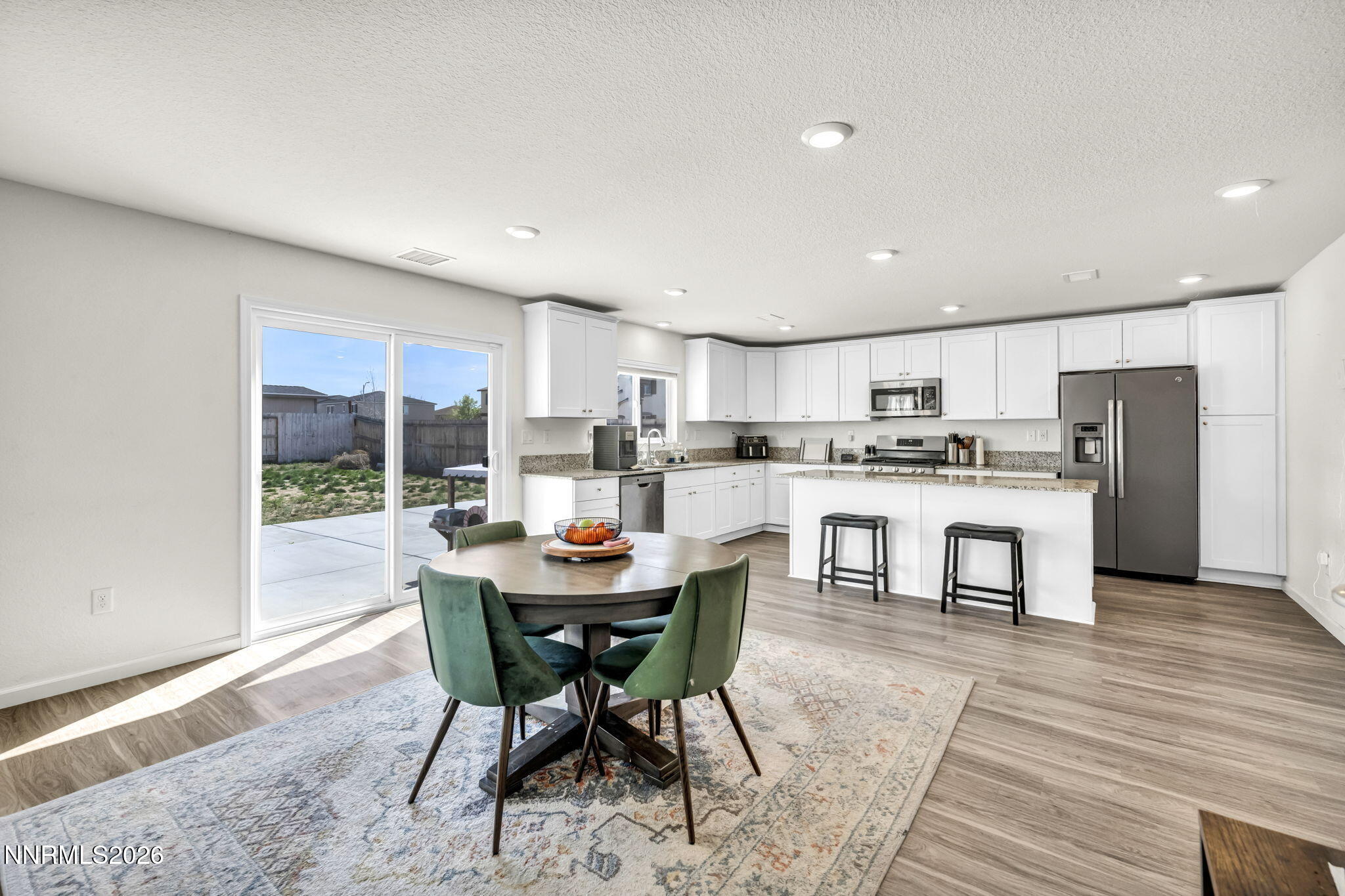 8982 Wolf River Drive Reno, NV 89506 - Photo 12 of 65 a kitchen with stainless steel appliances kitchen island granite countertop a table chairs and a refrigerator