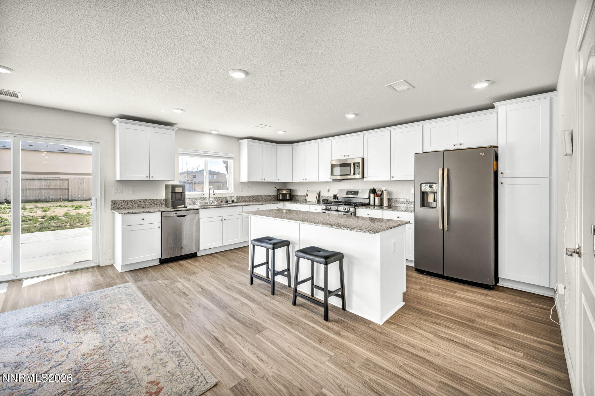 8982 Wolf River Drive Reno, NV 89506 - Photo 4 of 65 a kitchen with stainless steel appliances granite countertop a refrigerator a sink dishwasher a stove top oven a kitchen island and chairs with wooden floor