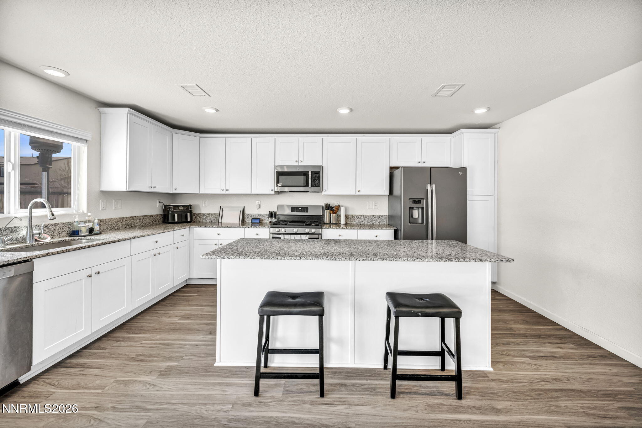 8982 Wolf River Drive Reno, NV 89506 - Photo 7 of 65 a kitchen with stainless steel appliances granite countertop a white cabinets and wooden floor
