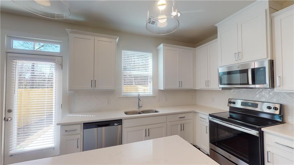 a kitchen with cabinets stainless steel appliances a sink and a window