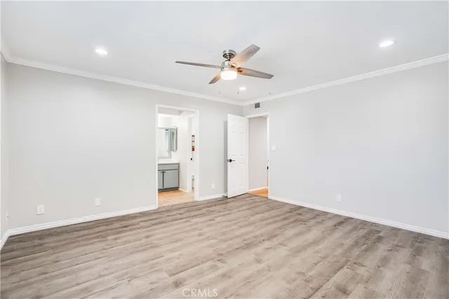 a view of an empty room with wooden floor and a ceiling fan