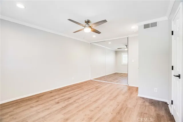a view of empty room with wooden floor and fan